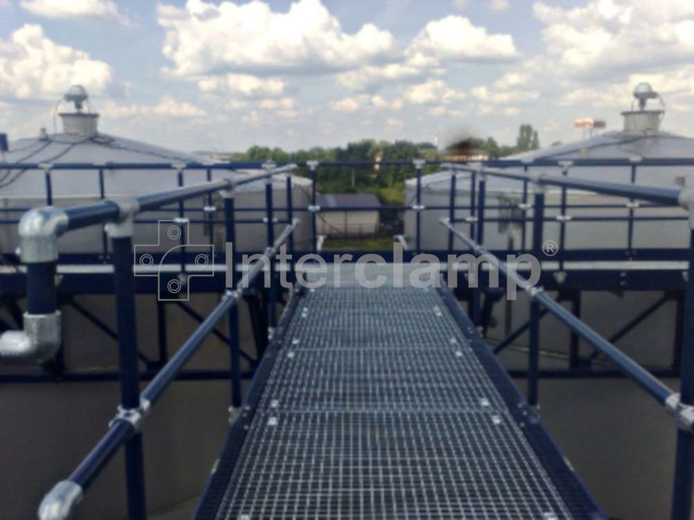 A chemical plant with secure walkways featuring safety guardrails constructed from Interclamp tube clamp fittings, prioritizing the well-being of employees.